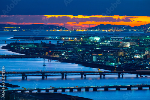 Japan. Evening in the Japanese city. Yodo river, bridges and houses against the sunset. Night in Osaka. Osaka road and railway bridges. Evening in Japan. Travelling to East Asia. © Grispb