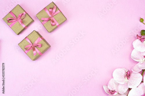 flat-lay of present gift boxes with pink ribbon on pink background with orchid flowers. spring concept. Copy space © olga_demina