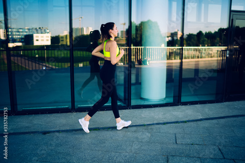 Strong active female jogger in active outfit having morning training motivated with reaching goals, caucasian sportswoman with perfect body shape running on cardio workout having energy and motivation