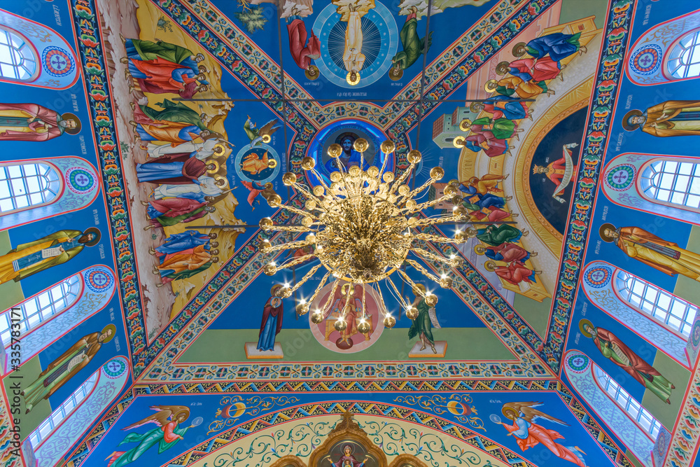 Eastern сhristian orthodox сhurch of Byzantine tradition. Traditional religious paintings and colorful  traceries on the ceiling. Huge golden chandelier