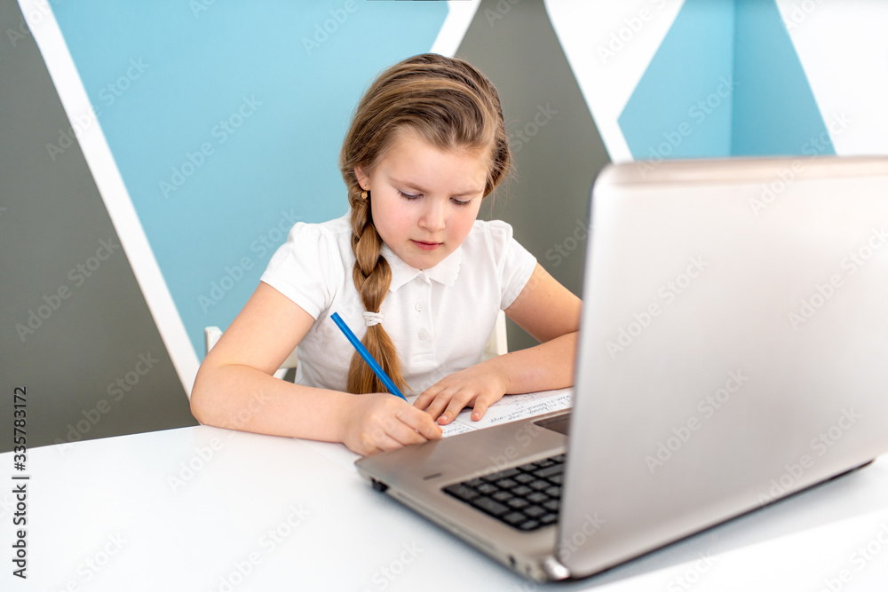 Distance learning online education. Schoolgirl studying at home with digital tablet laptop notebook and doing school homework. Sitting at the table with training books Distance learning online education. Schoolgirl studying at home with digital tablet laptop notebook and doing school homework. Sitting at the table with training books