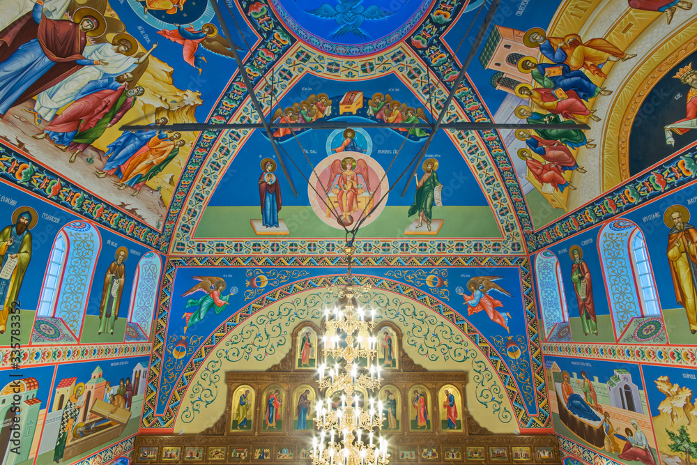 Eastern сhristian orthodox сhurch of Byzantine tradition. Traditional religious paintings and colorful  traceries on the ceiling. Huge golden chandelier