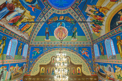 Eastern сhristian orthodox сhurch of Byzantine tradition. Traditional religious paintings and colorful traceries on the ceiling. Huge golden chandelier