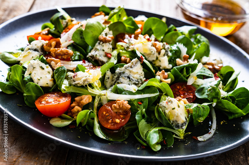 Fresh salad - blue cheese  cherry tomatoes  vegetables and walnuts on wooden background