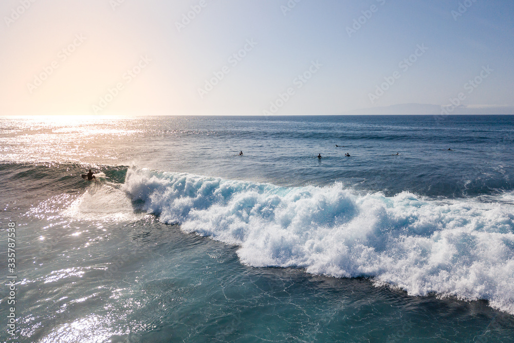 aerial view of a surfer riding a surf at sunset