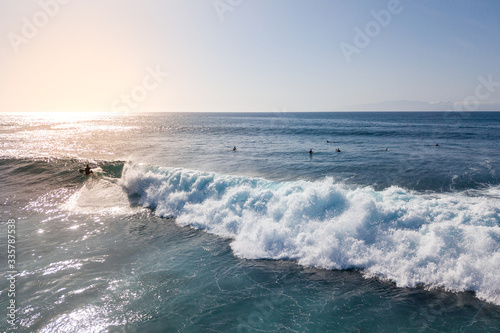 aerial view of a surfer riding a surf at sunset