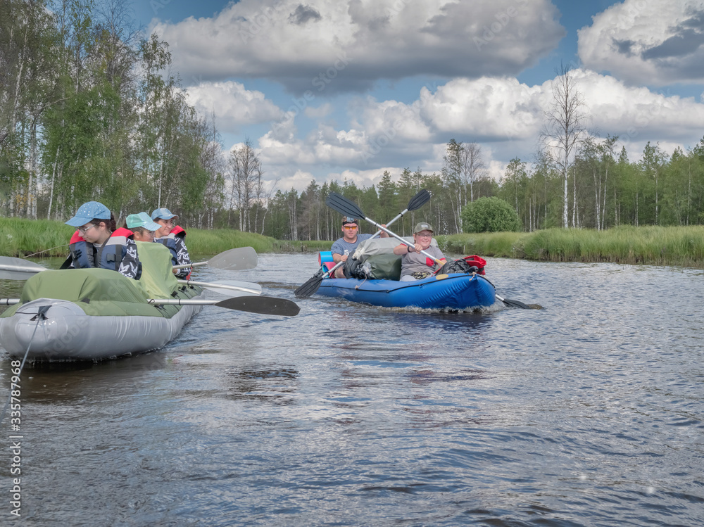 Fototapeta premium Karelia, Vodlozero - 29.07.2019: Tourists in boats. Ecotourism, visiting fragile, undisturbed natural areas. Active extreme holidays. Water rafting in North lakes and rivers