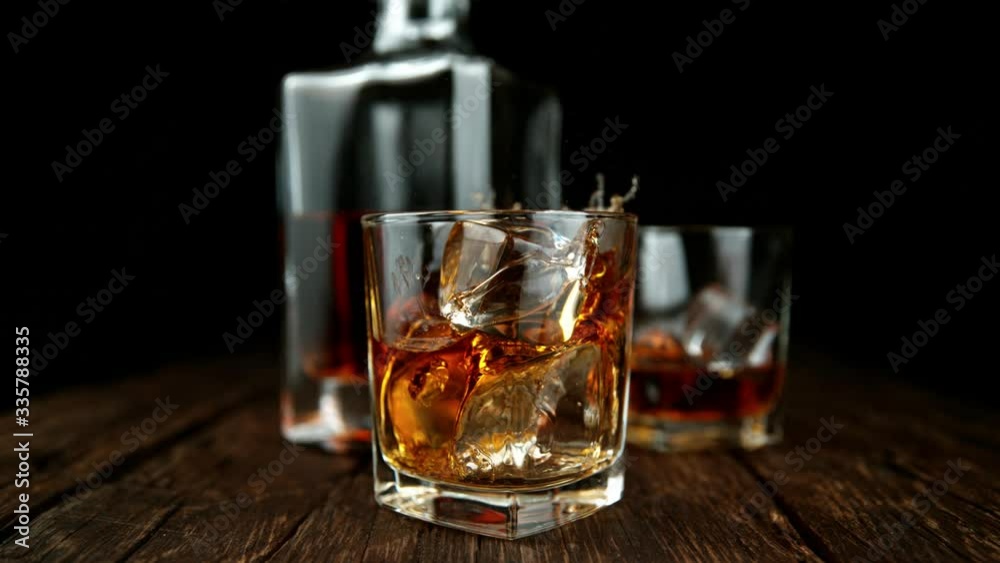 Super slow motion of falling ice cube into whiskey drink, camera motion. Filmed on high speed cinema camera, 1000fps Super slow motion of falling ice cube into whiskey drink, camera motion. Filmed on high speed cinema camera, 1000fps