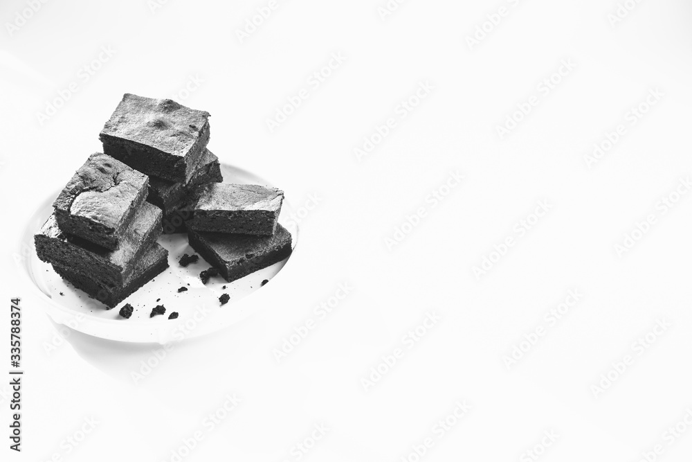 Chocolate brownie sliced into square slices on a white plate. Chocolate brownie sliced into square slices on a white plate.