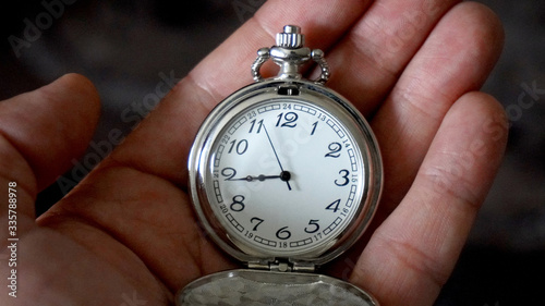 Old antique pocket watch showing time being held in hand. Close up
