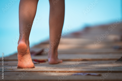 Close up barefoot girl posing walking relax on walkway bridge wood beach with sunlight shine © etemwanich