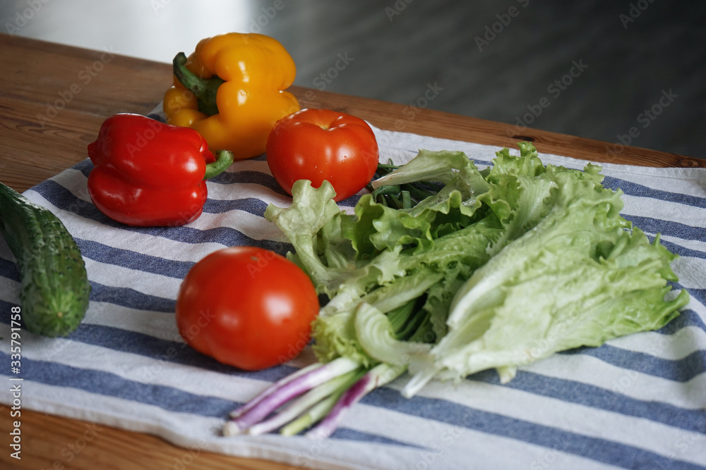Bunch of vegetables. Red pepper, tomato, cucumber and green salad on striped towel