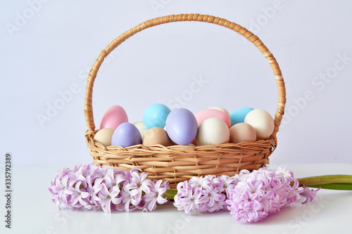 Colorful easter eggs in basket on pastel color background with flowers, copy space.Easter decorations. Easter background with painted eggs with Hyacinth, top view. Spring greeting card