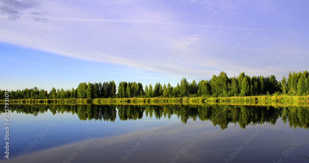 landscape. the sky and the green forest are reflected in the surface of the lake. horizontal photo