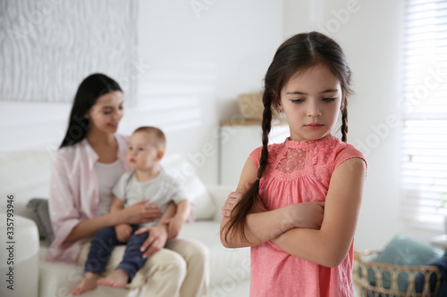 Foto Unhappy little girl feeling jealous while mother spending time with her baby bro