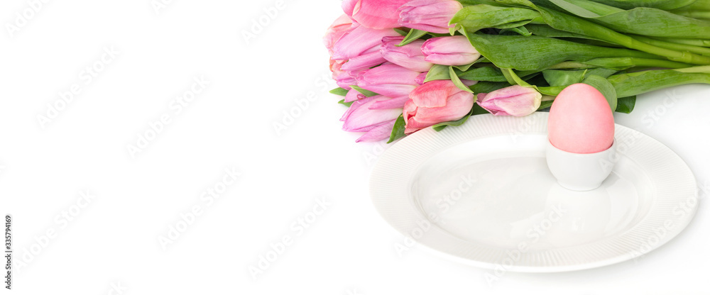 Easter table setting with spring flowers tulips and a pink Easter egg on a white background. Banner. Copy space.