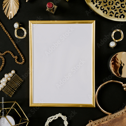 Golden blank frame with luxury golden accessories for women's beauty. Dating concept with red lipstick, roses, golden chain, earrings and handbag on black background. Elegant modern template for