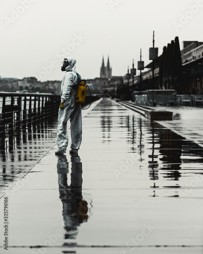 Man in a white protective suit and gas mask spray the street against Corona virus - Covid 19 