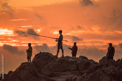 hombres pescando al atardecer en la playa 