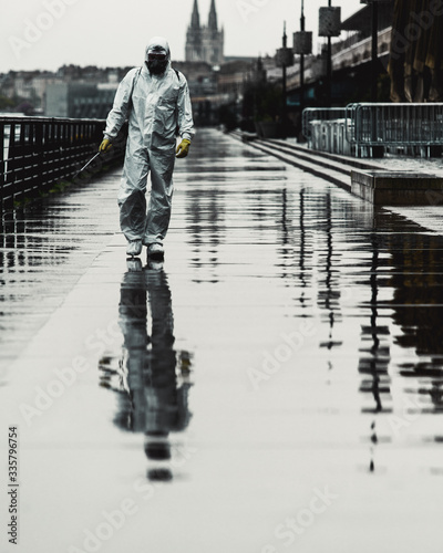Man in a white protective suit and gas mask spray the street against Corona virus - Covid 19 