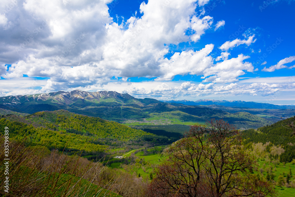 Beautiful mountain panorama with lush greens, blue skies, and puffy clouds