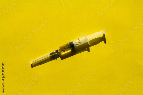 A syringe filled with medicine is located on a yellow background. photo