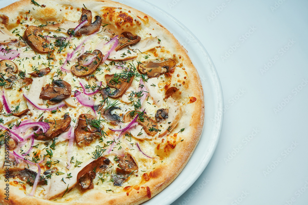 Appetizing baked Italian pizza with cream sauce, onions and mushrooms on a white plate isolated on gray background