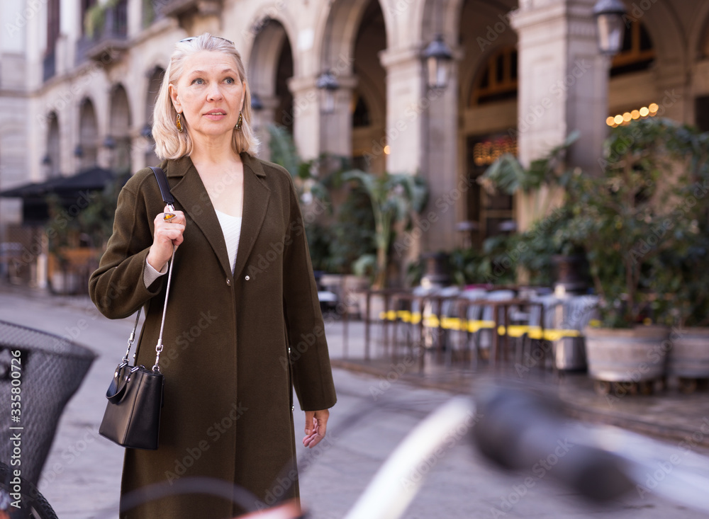 Fototapeta premium Portrait of smiling mature woman on street of old european city