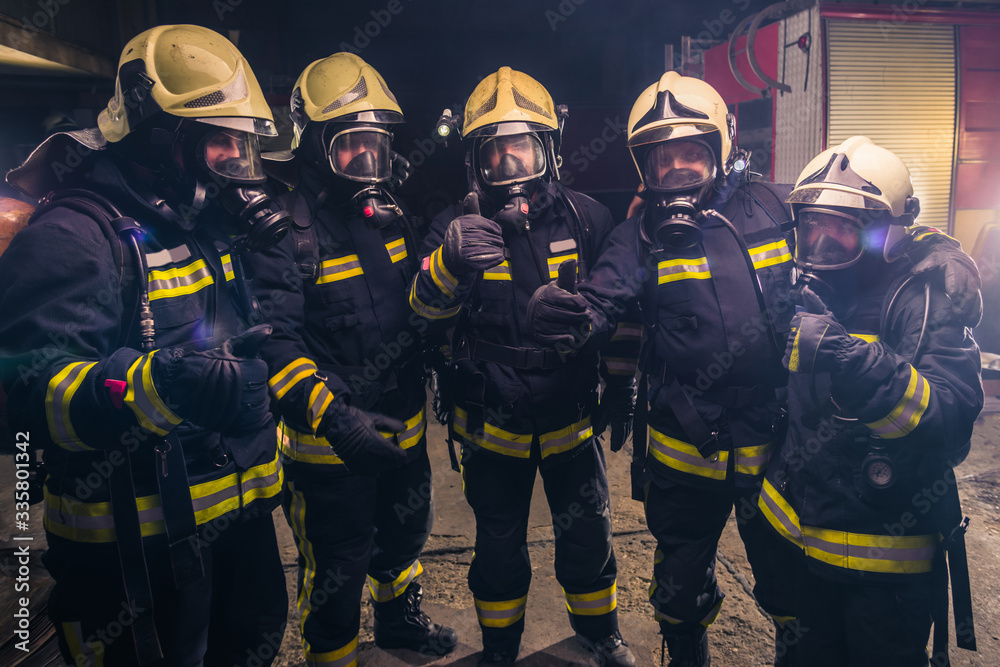 Team of firemen in uniform with gas masks inside the fire department Team of firemen in uniform with gas masks inside the fire department