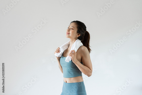 A young Asian woman wipes sweat with a towel in front of a pure white background
