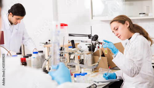 Woman lab technician writing report on chemical experiments