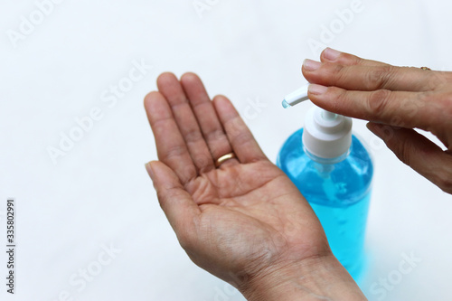 Female fingers pumping alcohol-based hand sanitizer gel on hand for killing germs  bacteria and virus. Disinfection concept of cleaning and washing hands with alcohol sanitizer. 