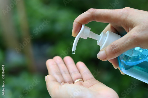 Female fingers pumping alcohol-based hand sanitizer gel on hand for killing germs, bacteria and virus. Disinfection concept of cleaning and washing hands with alcohol sanitizer
