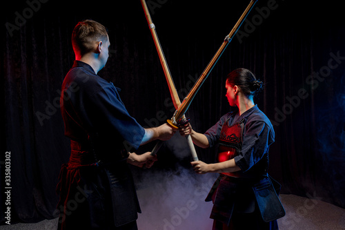 two kendo fighters opposite each other with shinai isolated over dark space. Japanese martial art of sword fighting. kendo concept. teacher or trainer and pupil