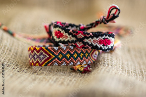 Group of handmade homemade colorful natural woven bracelets of friendship isolated on jute background