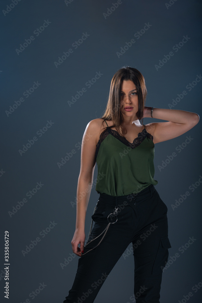 Portrait of a sexy young female model standing in a studio and wearing dark green top and black pants Portrait of a sexy young female model standing in a studio and wearing dark green top and black pants