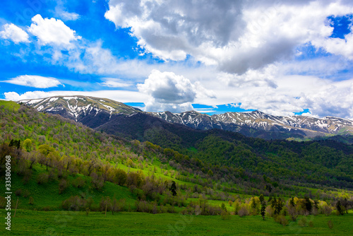 Beautiful mountain panorama with lush greens, blue skies, and puffy clouds