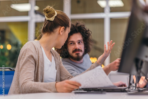 Two colleagues working on a project in modern startup offices. Guy with afro haircut and a female blonde employee working at the office.