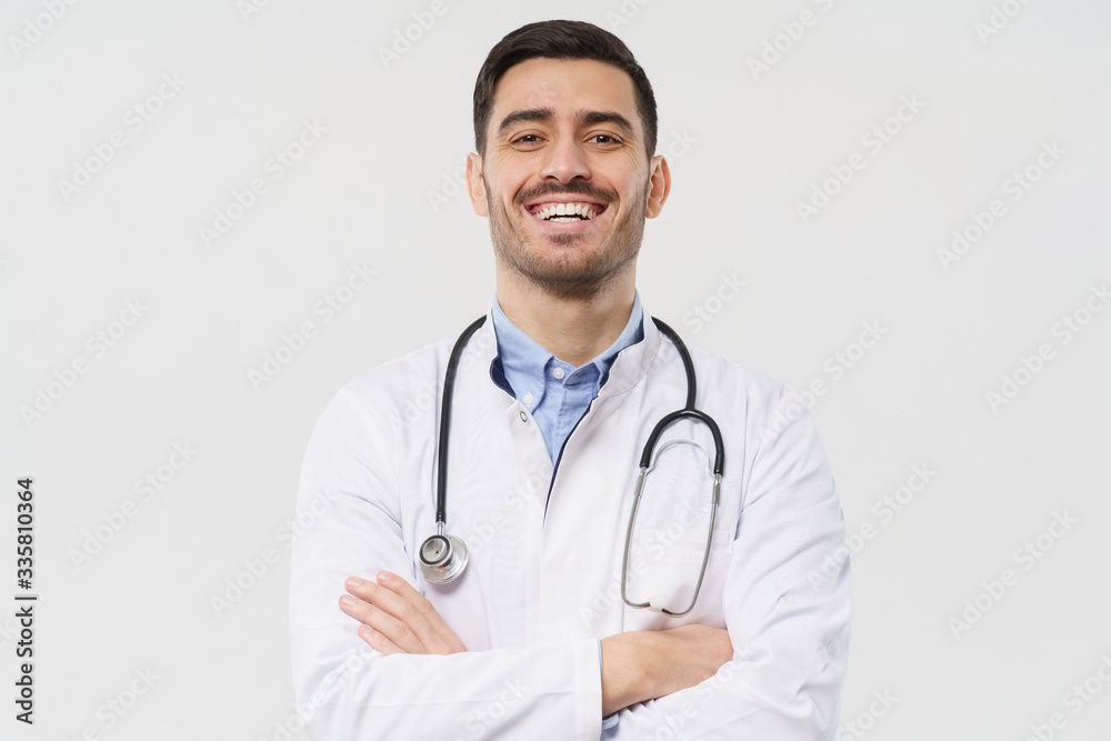 Close-up portrait of cheerful lauging young male doctor with stethoscope around neck, wearing white coat, isolated on gray background Close-up portrait of cheerful lauging young male doctor with stethoscope around neck, wearing white coat, isolated on gray background