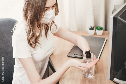 A young woman in a medical respiratory mask washes her hands with an antiseptic, alcohol solution, antibacterial spray, gel, coronavirus protection, hand hygiene, quarantine