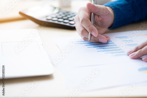 Businessman is inspecting the business reports graphs to audit the financial reports. Analyzing the revenue and auditing the budget concept.