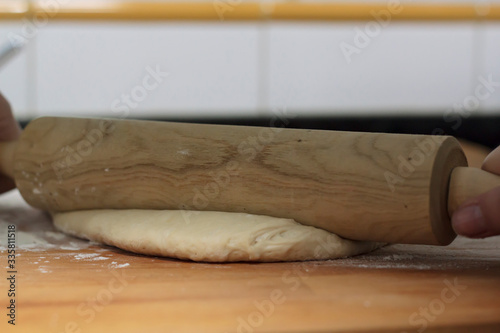 Woman hand kneading dough ball with rolling pin