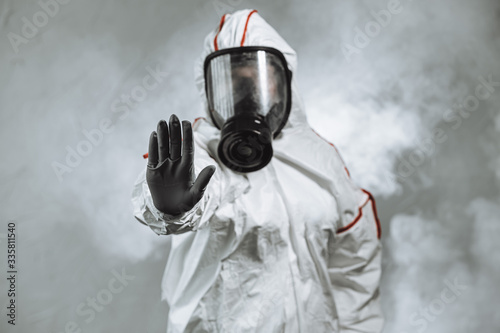 keep the distance, stop to coronavirus. disinfector male in gas-mask and protective suit disinfect contaminated areas full of bacterias. quarantine time photo