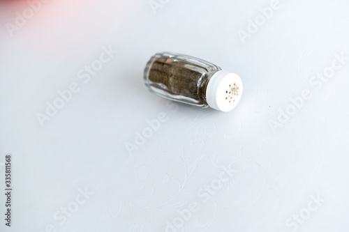 On a white background spice (pepper) in a glass container