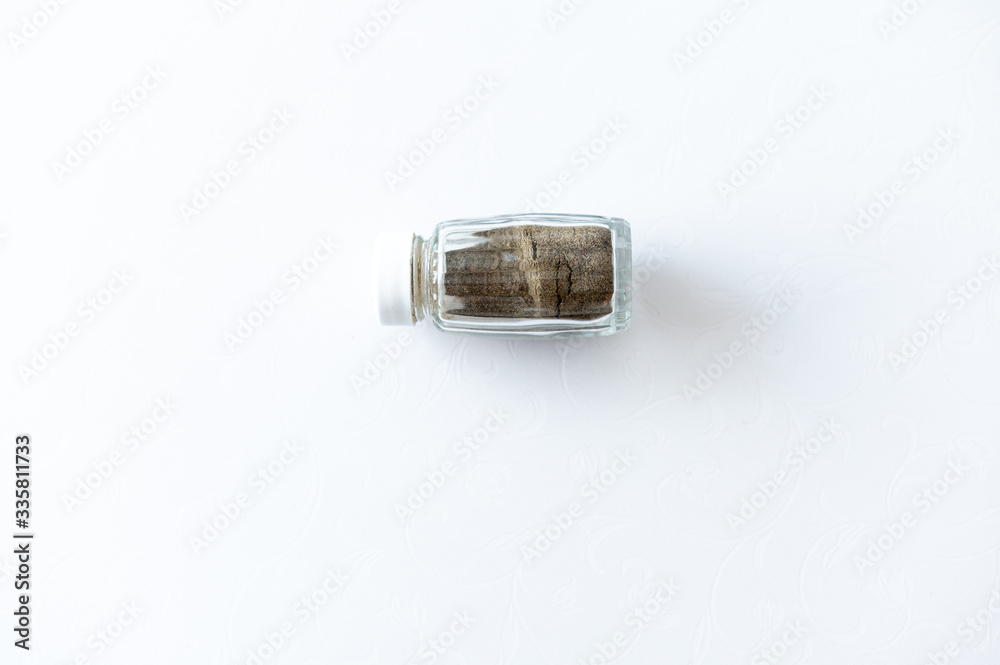 On a white background spice (pepper) in a glass container On a white background spice (pepper) in a glass container