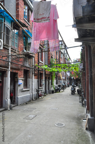 Insight into a residential path in Shanghai, China. The low residential buildings are called Shikumen. Laundry hangs in the alleys, scooters stand and people live here.