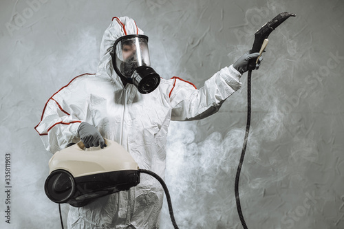 disinfector in a protective suit conducts disinfection in contaminated area. professional disinfection against COVID-19, coronavirus. in clothing protecting from chemical poisoning in the industry photo