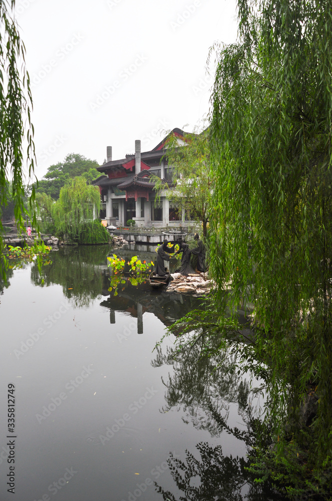 Obraz premium A Chinese building on the shores of West Lake in Hangzhou. The trees and the house are reflected in the water.