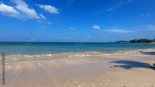 Relaxing on the beach near resort under palm trees on white sand Phra Ae long beach of Koh Lanta island, Krabi, Thailand. Small waves splattering and splashing on rocky coast. Sunny day. Full HD.