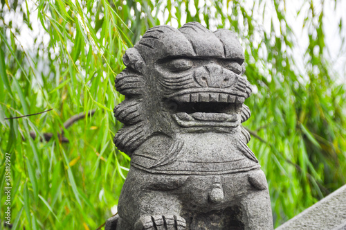 Dragon head statue at a bridgte is facing with fog in the background. Selected Focus on dragon head. Background is foliage.